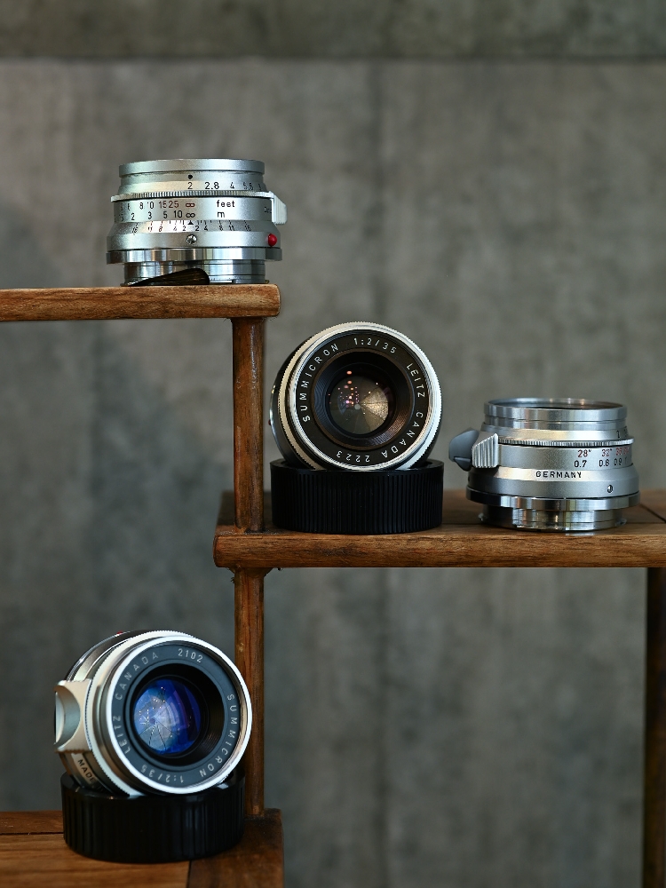 Four Leica Summicron 35mm f/2 8-element lenses showing Canada and Germany production and different coatings