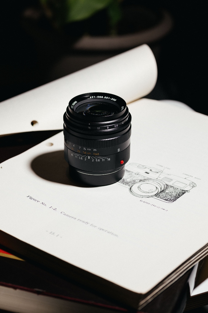 Leica Summicron-M 66mm f/2 limited edition standing on an open KE-7A technical manual showing a line drawing of the camera